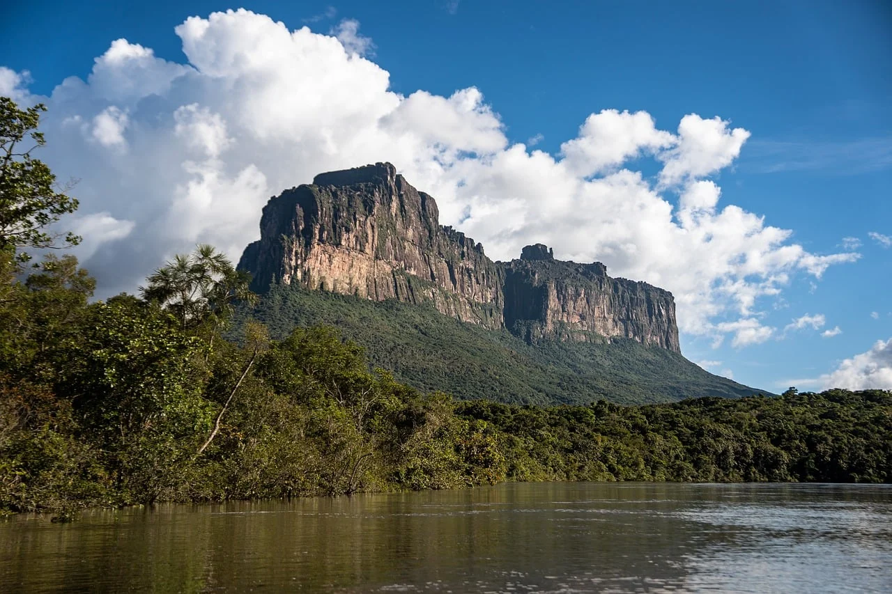 Tepuy en Canaima con vegetación verde, río y cielo azul